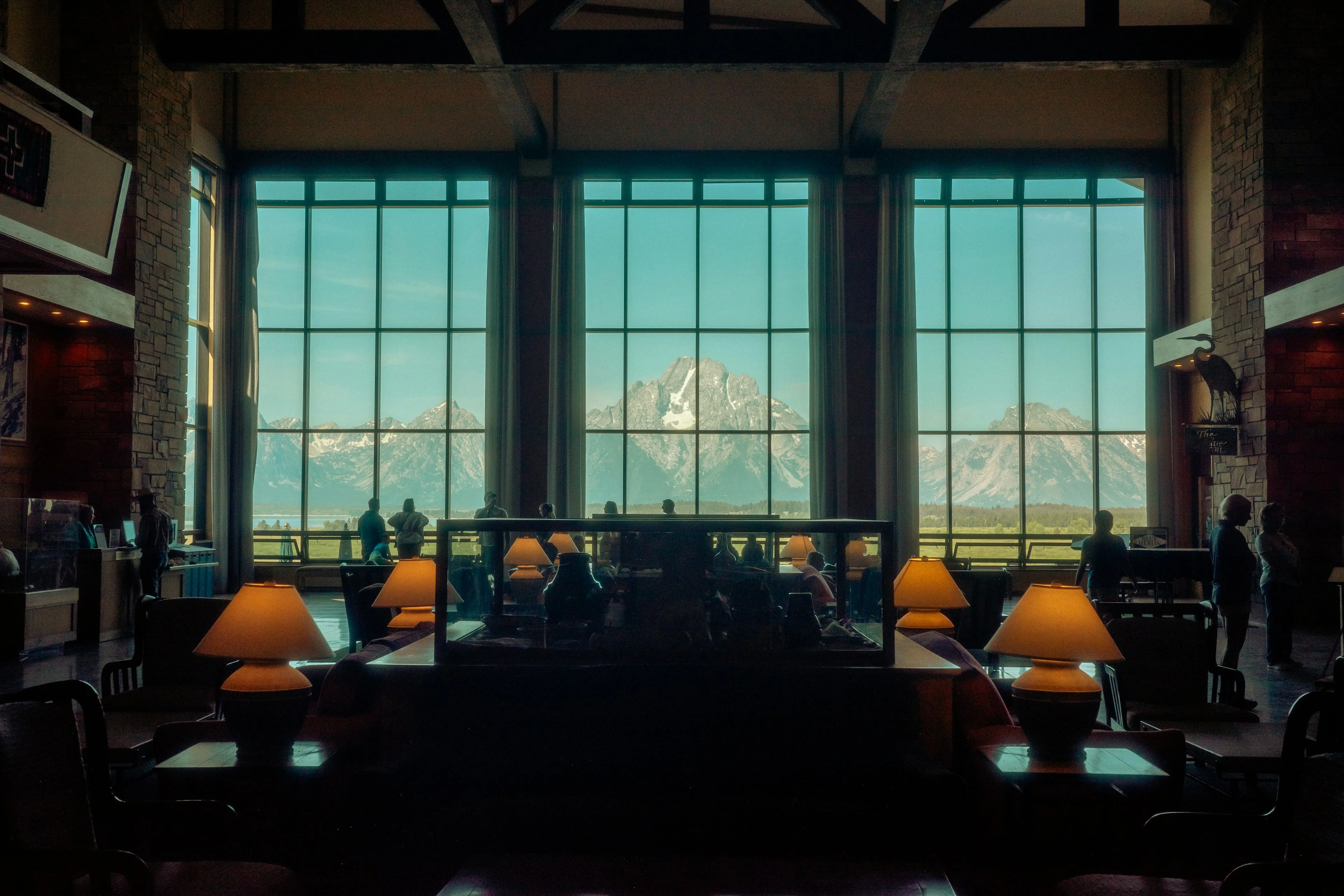 A handsome lodge interior with large windows overlooking the mountains.